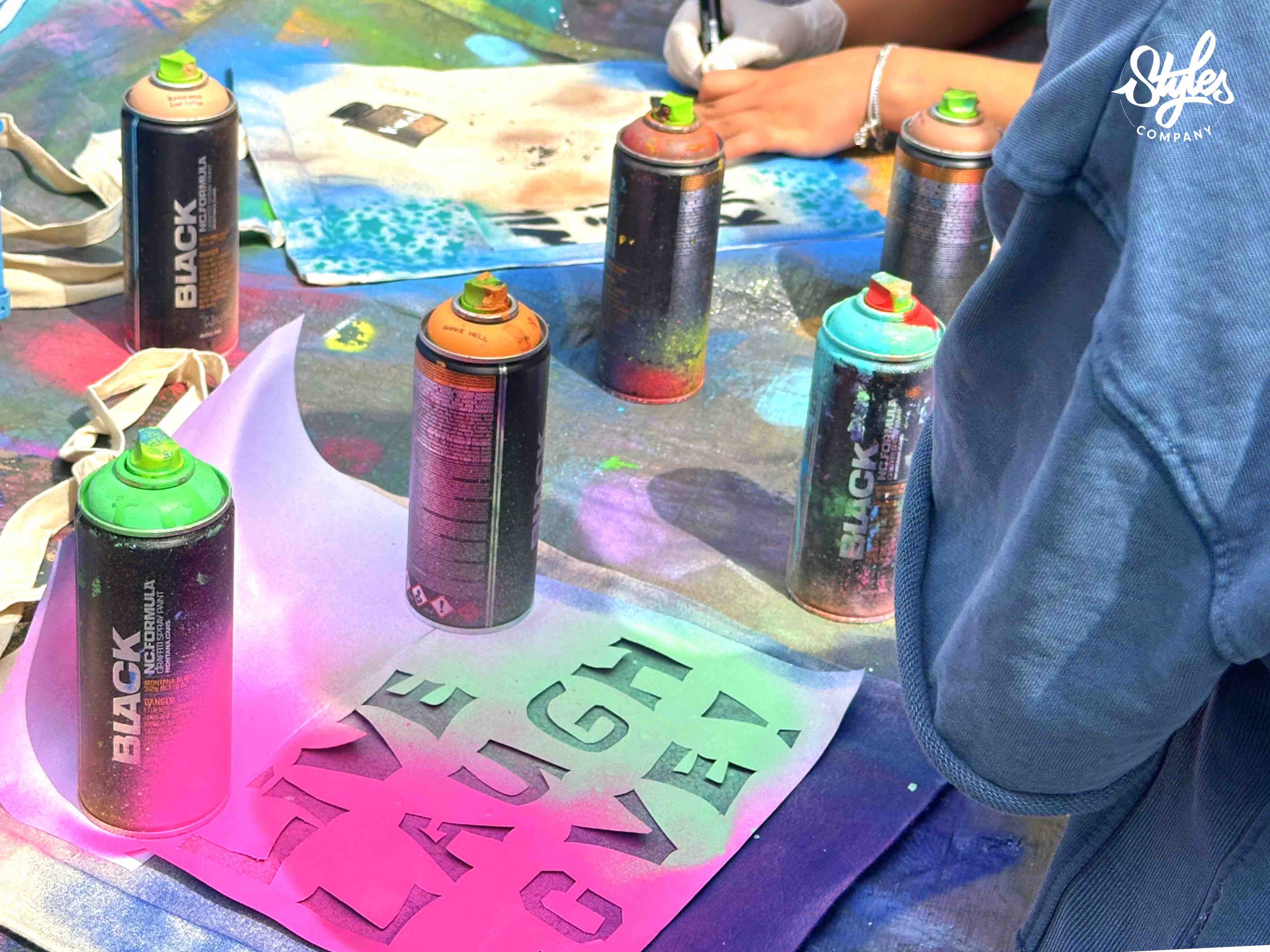 Stencils, spuitbussen en kleurrijke ontwerpen op een werktafel