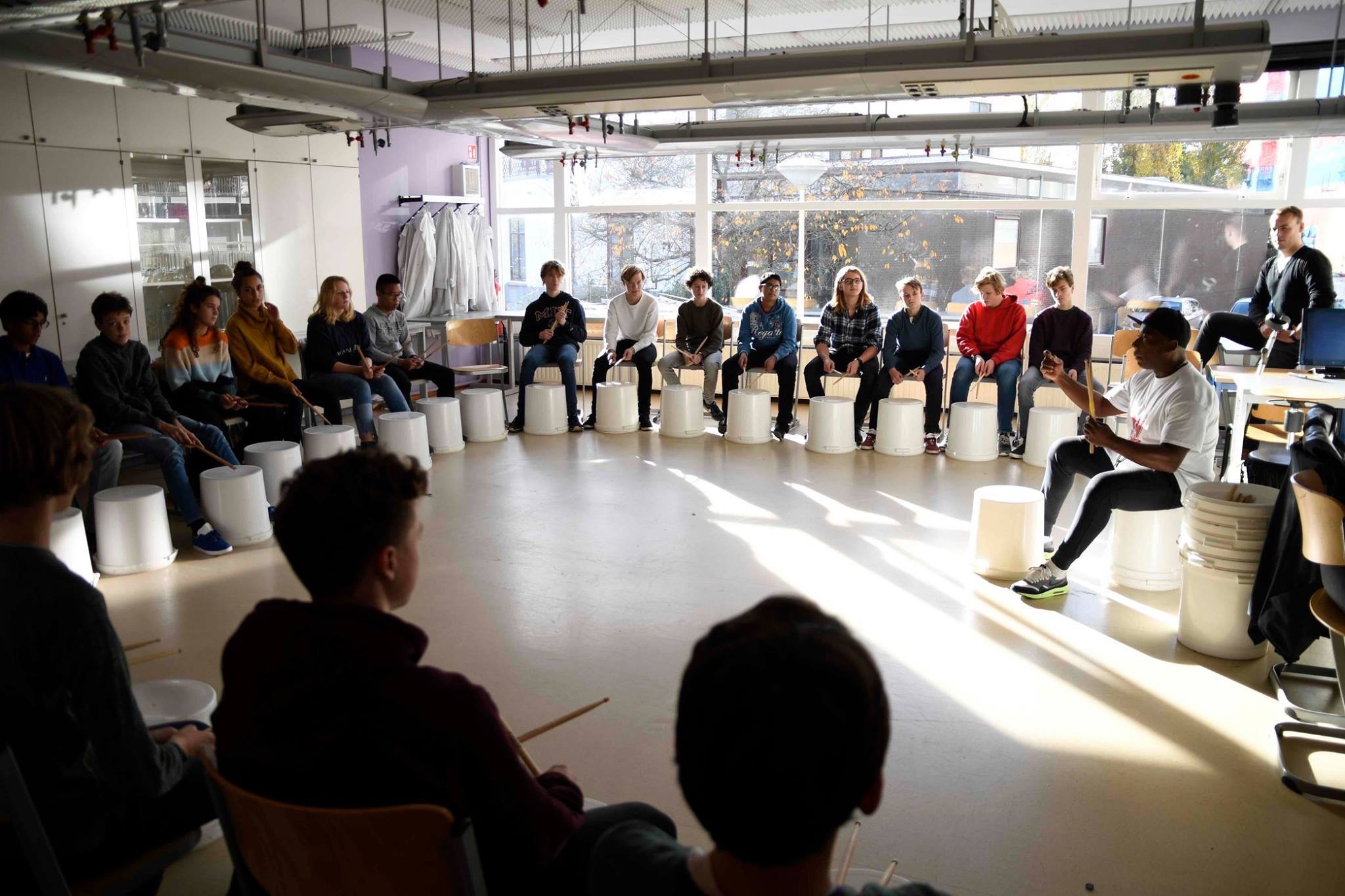 ['Samen aan de slag met stencils en spuitverf tijdens een Styles Company workshop', 'Deelnemers maken samen ritme tijdens een percussieworkshop']
